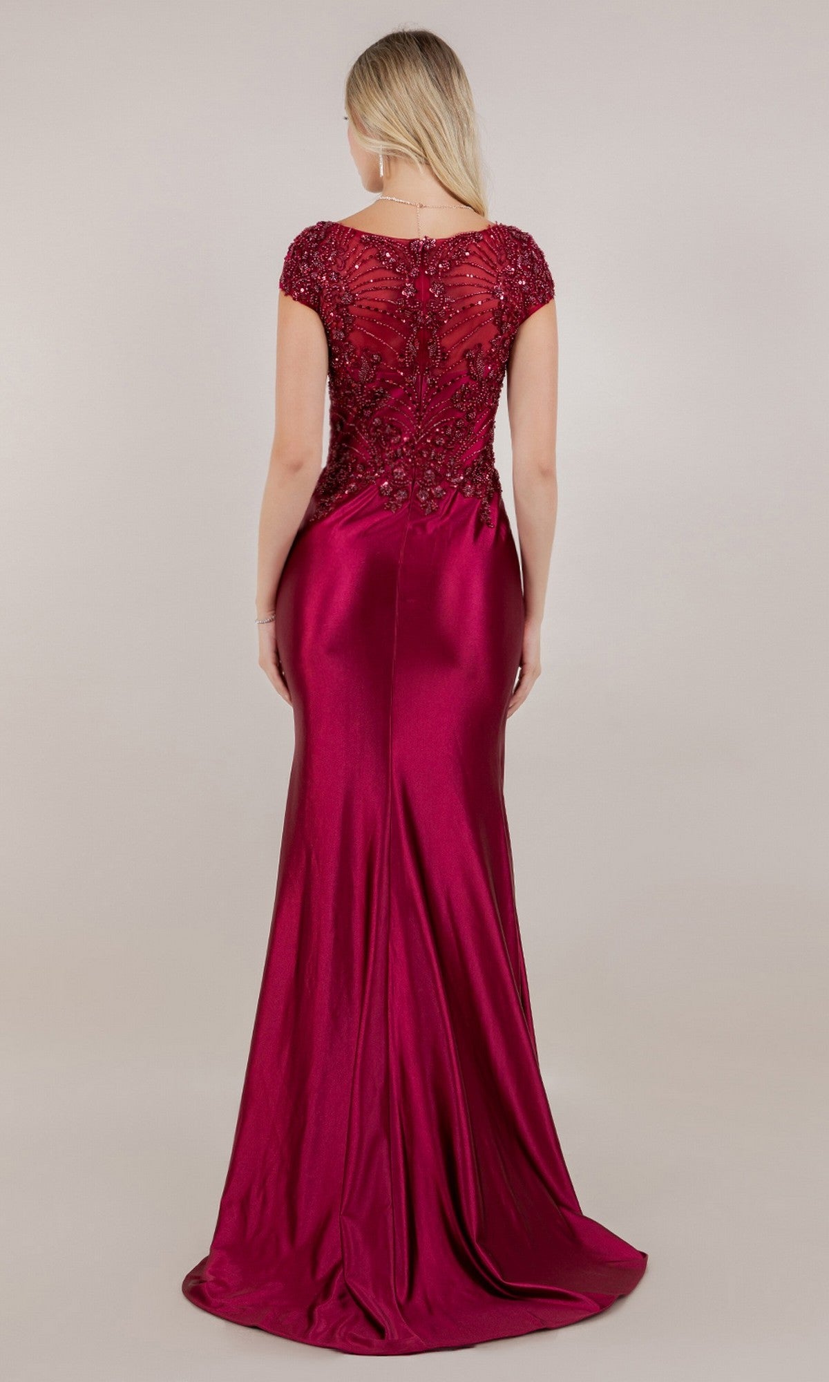 A woman is shown from the back in the Long Formal Dress: Cinderella Couture 8513M, a floor-length, short-sleeved burgundy beaded gown with a fitted bodice and an elegant satin skirt, against a plain background.